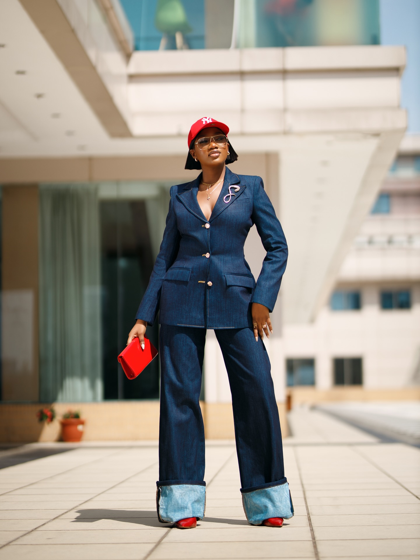 Fitted dark-wash denim-on-denim workwear set with gold buttons and red accessories.